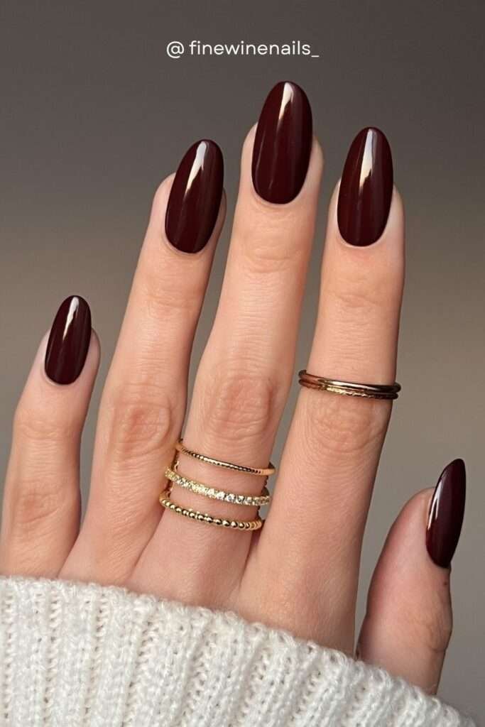 A longer almond version of the signature fall burgundy. Studio lighting shows off the incredible depth of this nail color — it reads almost black in shadow but glows ruby red in the light.