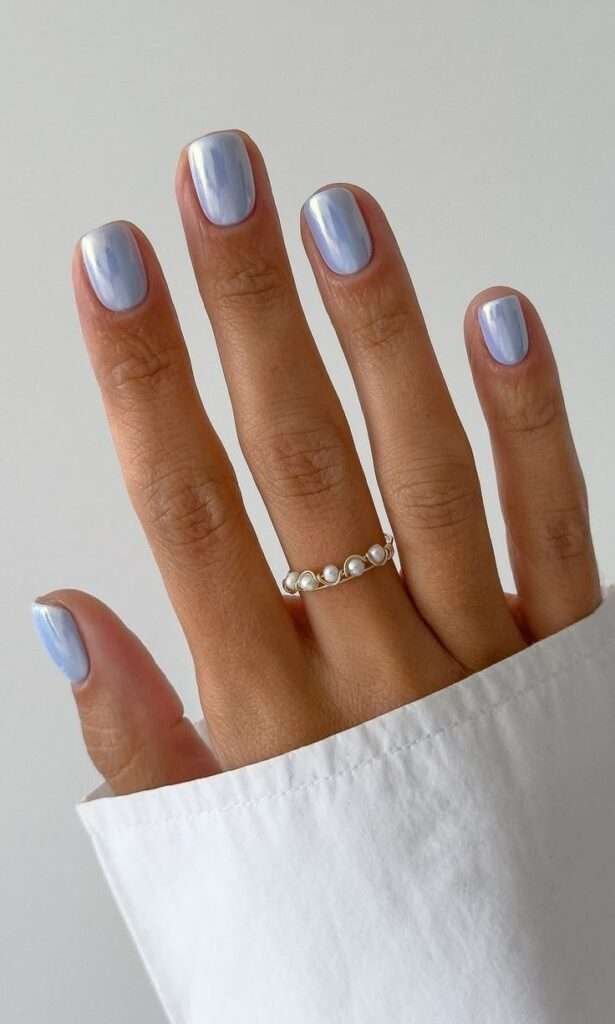 This chic look pairs a modern, short squoval shape with a refreshing, pale baby-blue base coat. It is layered with a fine white-silver chrome powder that gives the nails a metallic, liquid-pearl finish perfect for cooling down a hot July day.