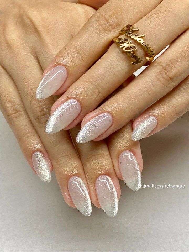 This ultra-luxurious manicure elevates a timeless almond shape with a magnetic cat-eye polish that mimics the dimensional shimmer of crushed velvet. The soft champagne and milky white tones blend beautifully against a sheer nude base, concentrating a velvety band of light along the tips for an ethereal French-ombre effect.
