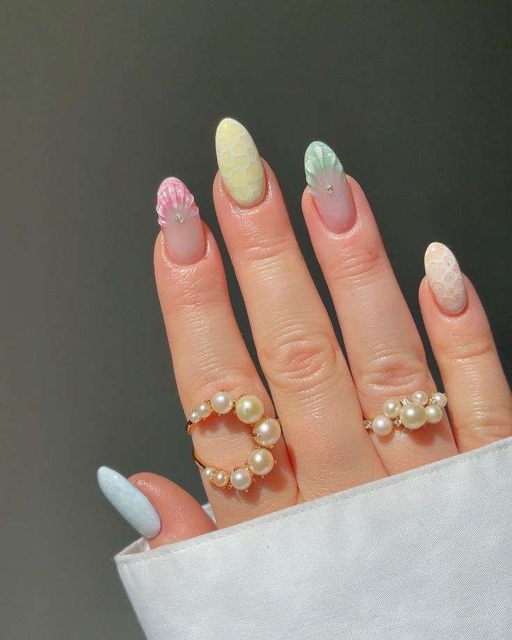 This luxury design blends textured 3D seashell accents and subtle bubble patterns to evoke a sophisticated, ocean-inspired aesthetic. A soft palette of pastel pink, mint green, and pale yellow elevates the almond-shaped tips into wearable summer art.