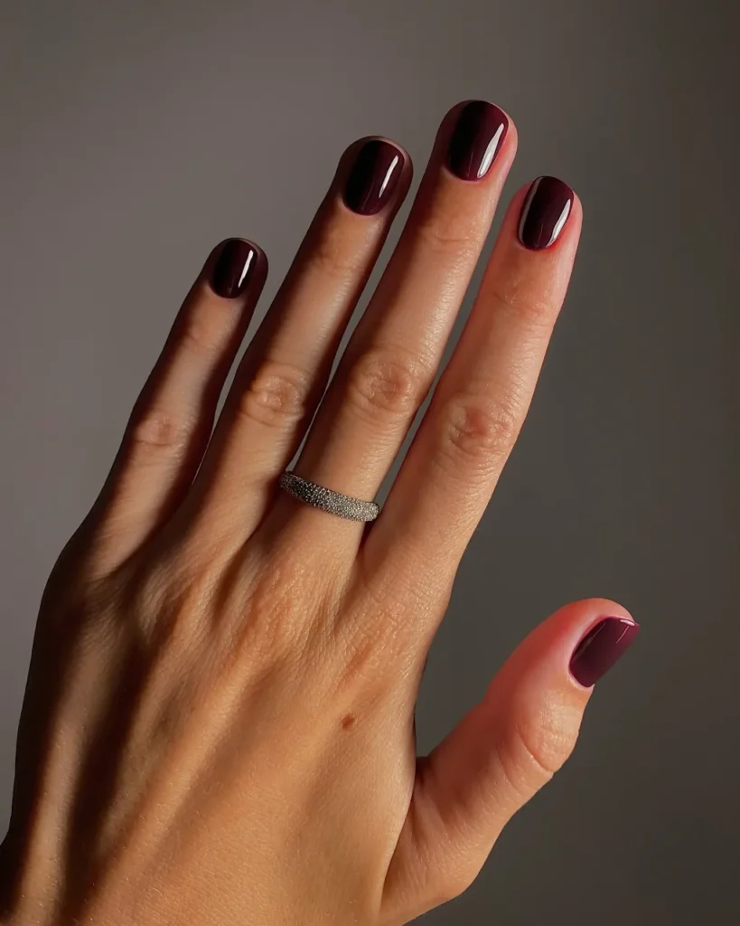 Short square nails in a solid, glossy oxblood polish.