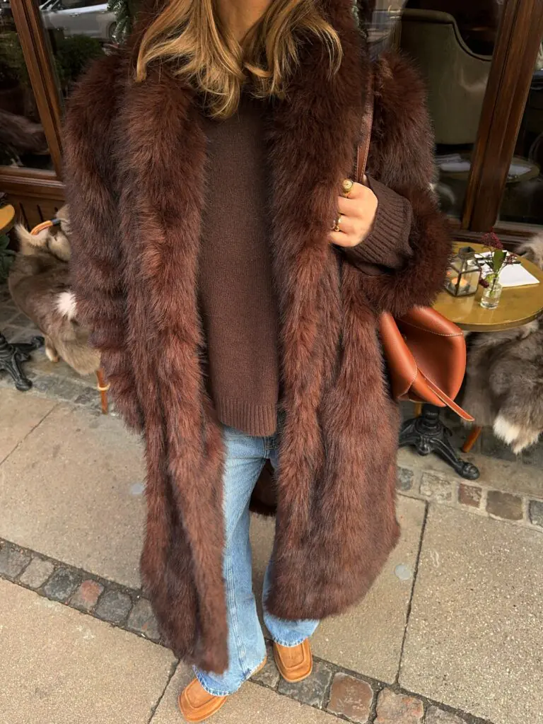 For days when you want your outerwear to do all the talking, a chocolate-brown faux-fur coat makes an excellent starting point. Its rich color and plush texture create an instantly elevated feel, especially when paired with a simple brown knit and light-wash jeans. The cognac shoulder bag and matching warm-toned shoes complement the coat without competing with it. This outfit is a reminder that winter styling doesn't always need complicated layers or bold prints; beautiful textures and a cohesive color palette can be just as effective.