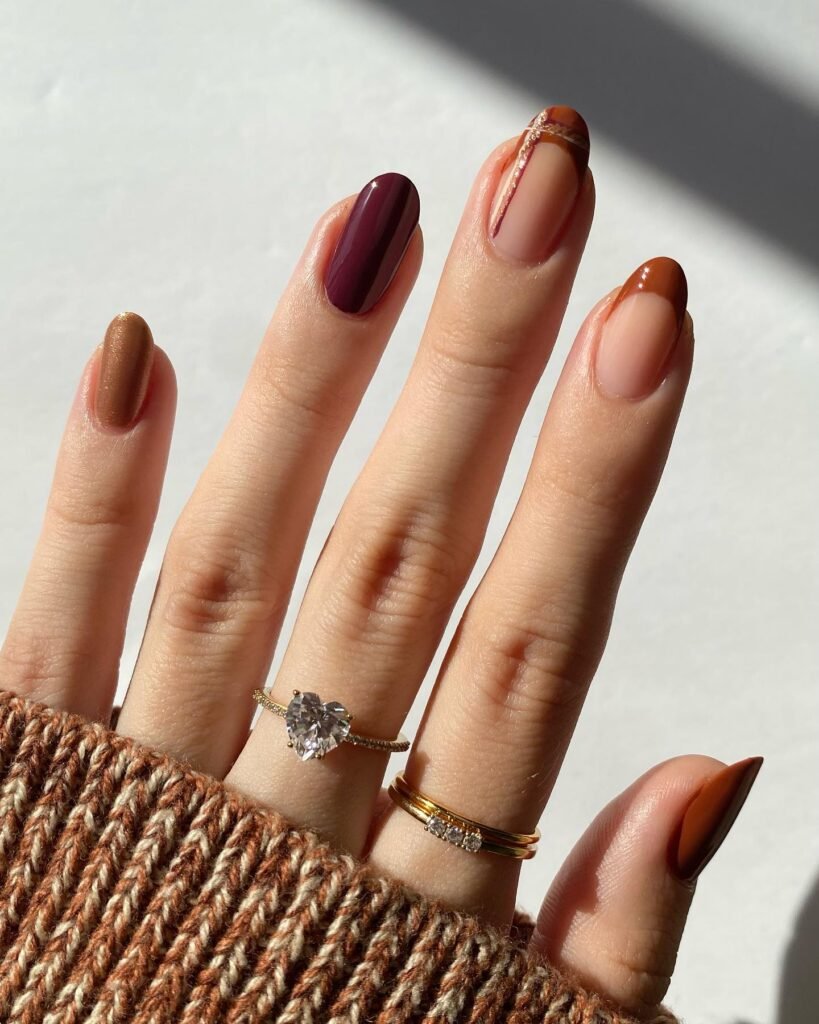 Plum, Copper and Soft Plaid French Tips. These two photos show one set from two angles, and it’s worth looking at both. There’s a plum nail, a copper shimmer, a rust French tip and a plaid French tip, with thin lines drawn over a sheer base. That last nail is the star: the plaid is only suggested, not filled in, so it feels light rather than heavy.