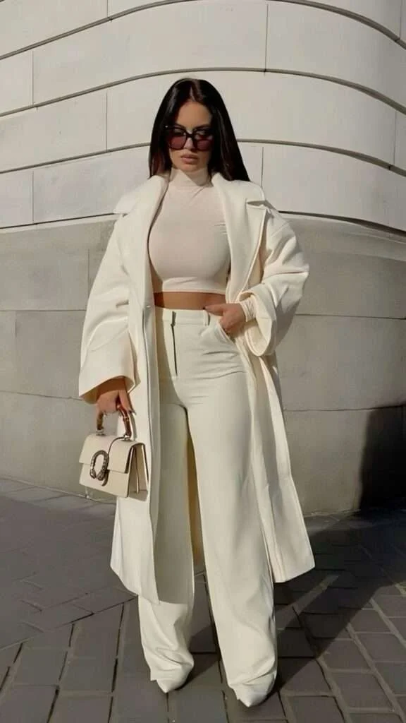 This outfit radiates contemporary elegance with its monochromatic cream palette. The oversized coat adds a layer of sophistication, while the fitted crop top and high-waisted pants create a flattering, streamlined silhouette.